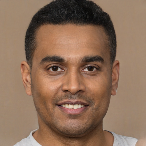 Joyful latino young-adult male with short  black hair and brown eyes