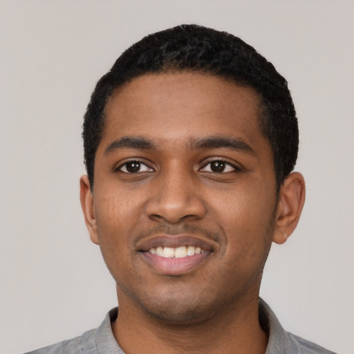 Joyful black young-adult male with short  black hair and brown eyes