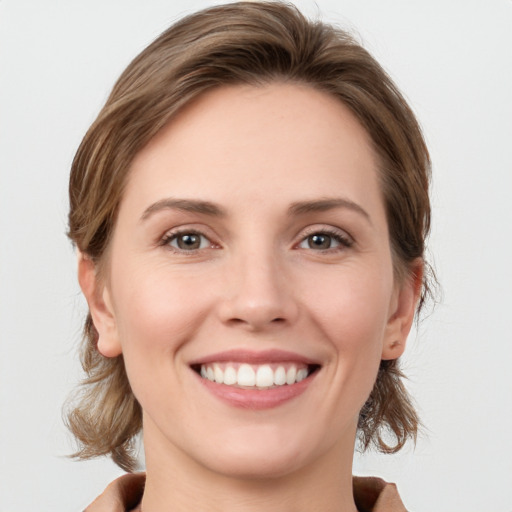 Joyful white young-adult female with medium  brown hair and grey eyes