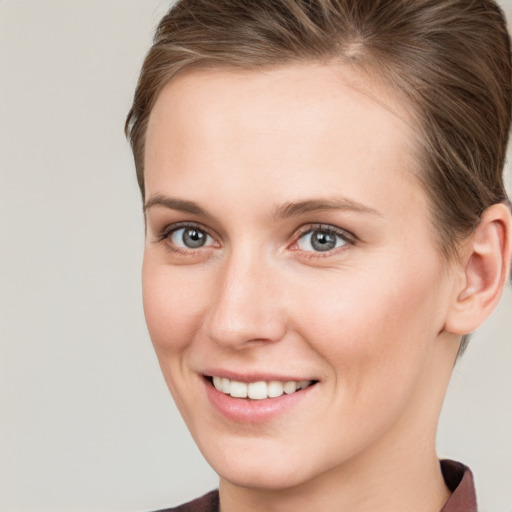 Joyful white young-adult female with short  brown hair and grey eyes