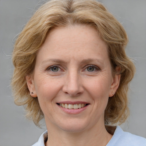 Joyful white adult female with medium  brown hair and blue eyes