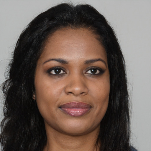 Joyful black young-adult female with long  brown hair and brown eyes