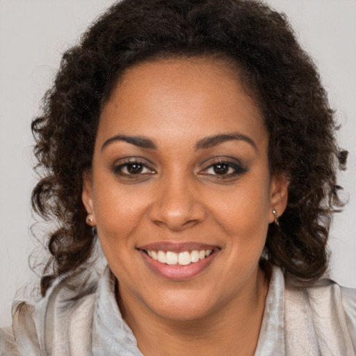 Joyful black young-adult female with long  brown hair and brown eyes