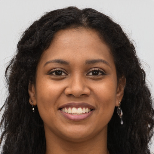 Joyful black young-adult female with long  brown hair and brown eyes