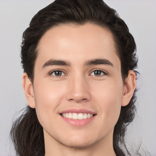 Joyful white young-adult male with long  brown hair and brown eyes