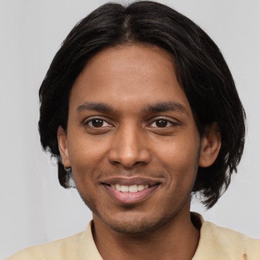 Joyful black young-adult male with medium  black hair and brown eyes