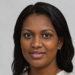 Joyful black young-adult female with long  brown hair and brown eyes