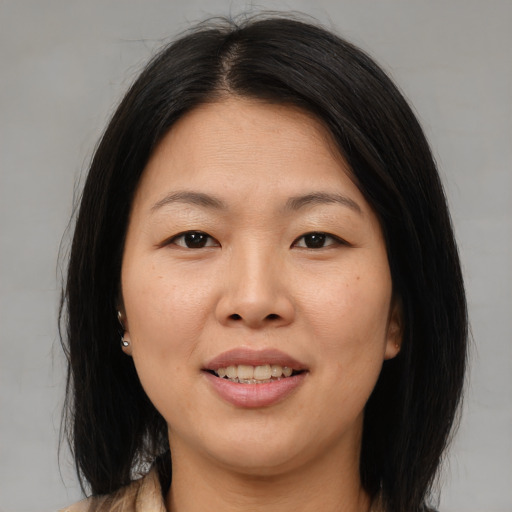 Joyful asian adult female with medium  brown hair and brown eyes