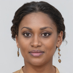 Joyful black young-adult female with long  brown hair and brown eyes