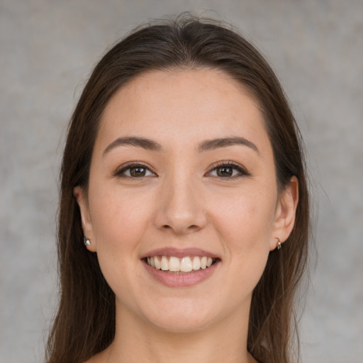 Joyful white young-adult female with long  brown hair and brown eyes