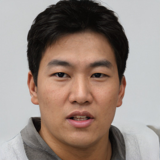Joyful asian young-adult male with short  black hair and brown eyes