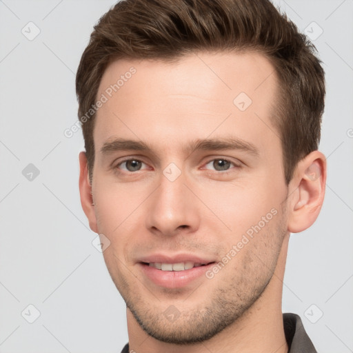 Joyful white young-adult male with short  brown hair and grey eyes