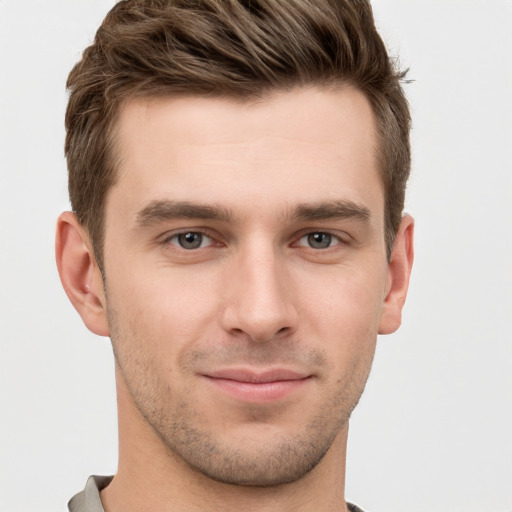 Joyful white young-adult male with short  brown hair and grey eyes