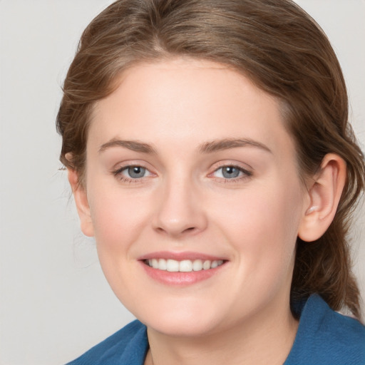 Joyful white young-adult female with medium  brown hair and grey eyes