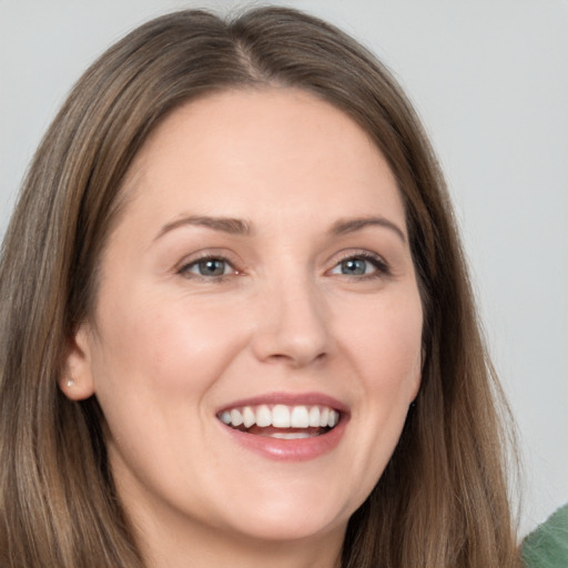 Joyful white young-adult female with long  brown hair and grey eyes