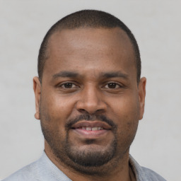 Joyful black young-adult male with short  brown hair and brown eyes