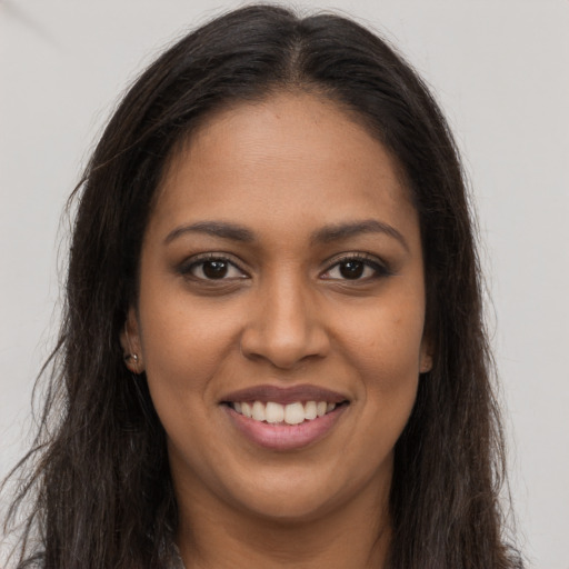 Joyful black young-adult female with long  brown hair and brown eyes