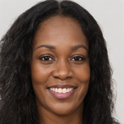 Joyful black young-adult female with long  brown hair and brown eyes