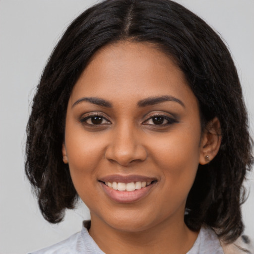 Joyful black young-adult female with medium  black hair and brown eyes