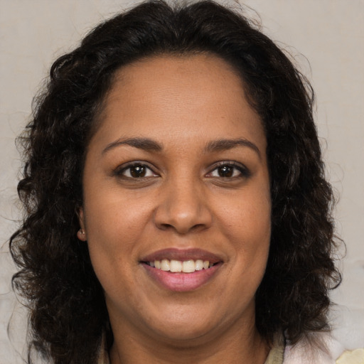 Joyful black adult female with long  brown hair and brown eyes