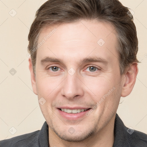 Joyful white adult male with short  brown hair and grey eyes