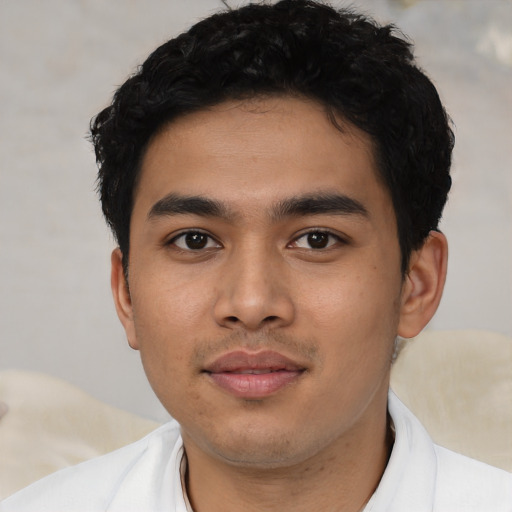 Joyful latino young-adult male with short  black hair and brown eyes