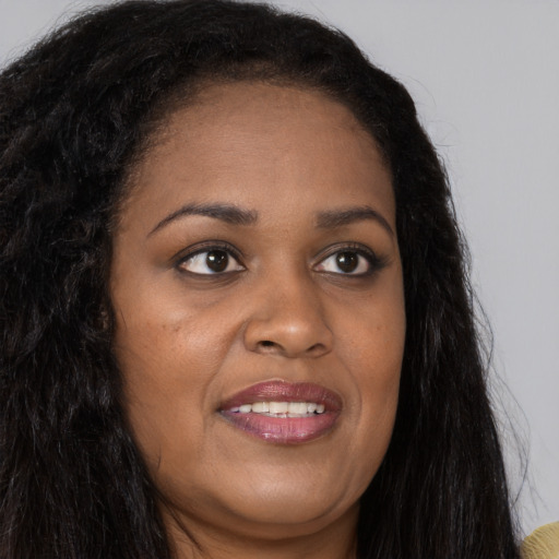 Joyful black young-adult female with long  brown hair and brown eyes