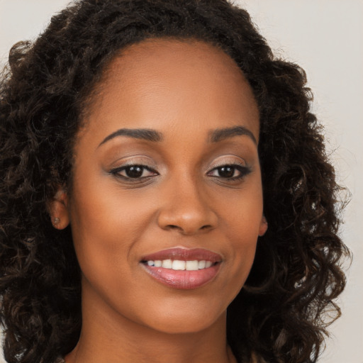 Joyful black young-adult female with long  brown hair and brown eyes