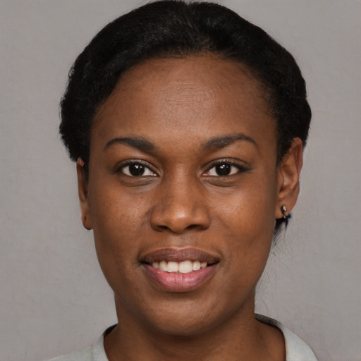 Joyful black young-adult female with short  black hair and brown eyes