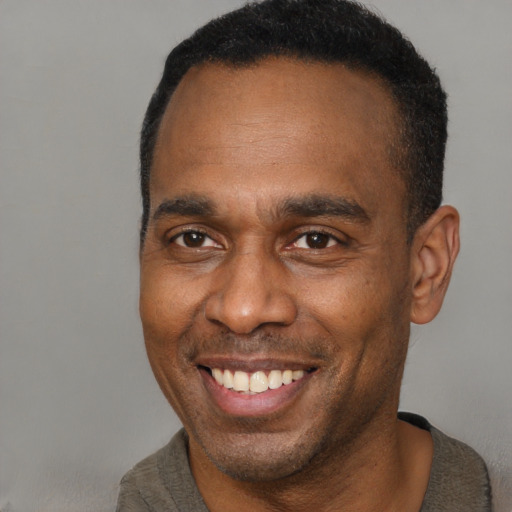 Joyful black adult male with short  brown hair and brown eyes