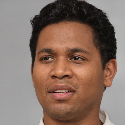 Joyful black young-adult male with short  black hair and brown eyes