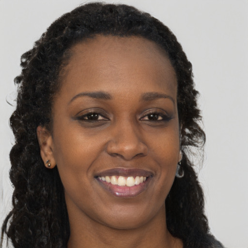 Joyful black young-adult female with long  brown hair and brown eyes