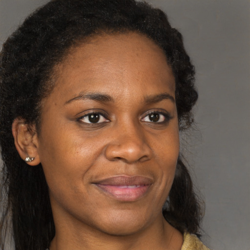 Joyful black adult female with long  brown hair and brown eyes