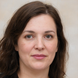 Joyful white adult female with long  brown hair and grey eyes