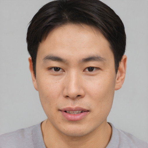 Joyful asian young-adult male with short  brown hair and brown eyes