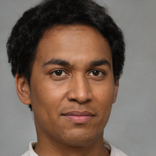 Joyful latino young-adult male with short  brown hair and brown eyes