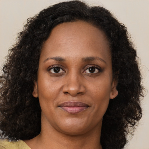 Joyful black adult female with long  brown hair and brown eyes
