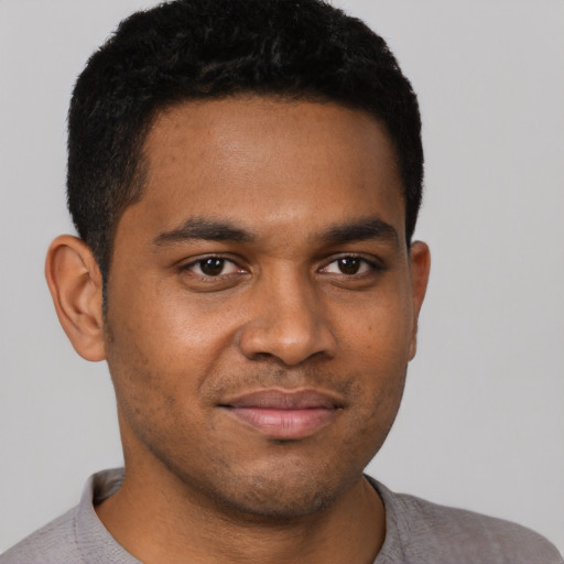 Joyful black young-adult male with short  black hair and brown eyes