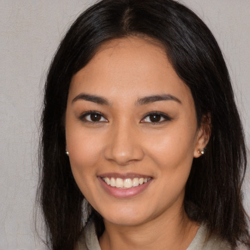 Joyful latino young-adult female with long  brown hair and brown eyes