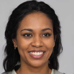 Joyful black young-adult female with long  brown hair and brown eyes