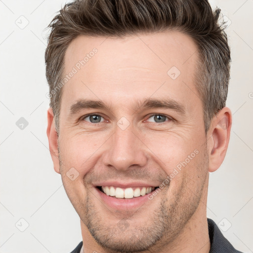 Joyful white adult male with short  brown hair and grey eyes