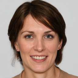 Joyful white adult female with medium  brown hair and grey eyes