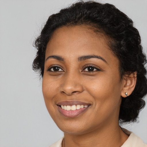 Joyful black young-adult female with long  brown hair and brown eyes