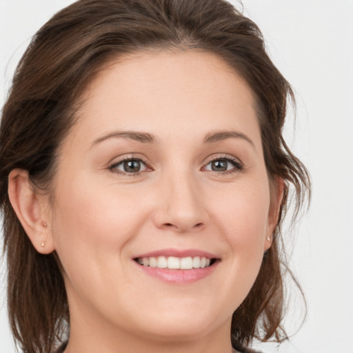 Joyful white young-adult female with medium  brown hair and grey eyes