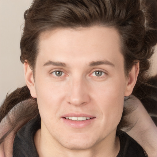 Joyful white young-adult male with long  brown hair and brown eyes