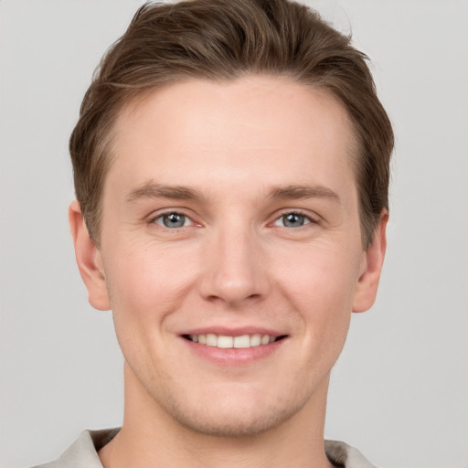 Joyful white young-adult male with short  brown hair and grey eyes