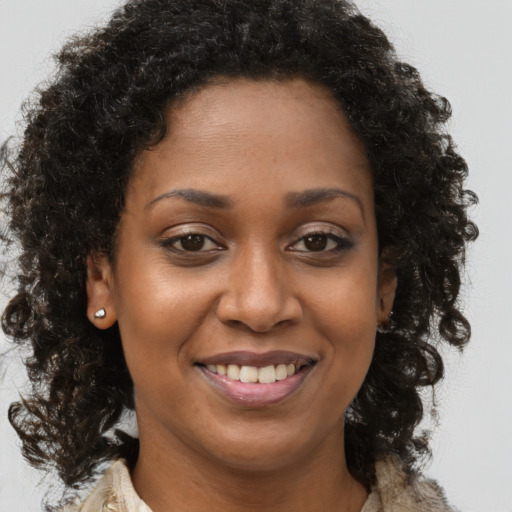 Joyful black young-adult female with long  brown hair and brown eyes