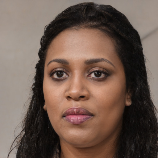 Joyful black young-adult female with long  black hair and brown eyes