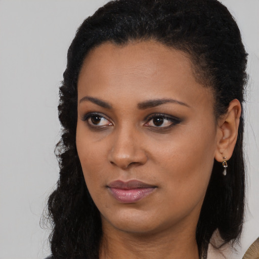 Joyful black young-adult female with long  brown hair and brown eyes