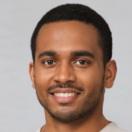 Joyful black young-adult male with short  black hair and brown eyes
